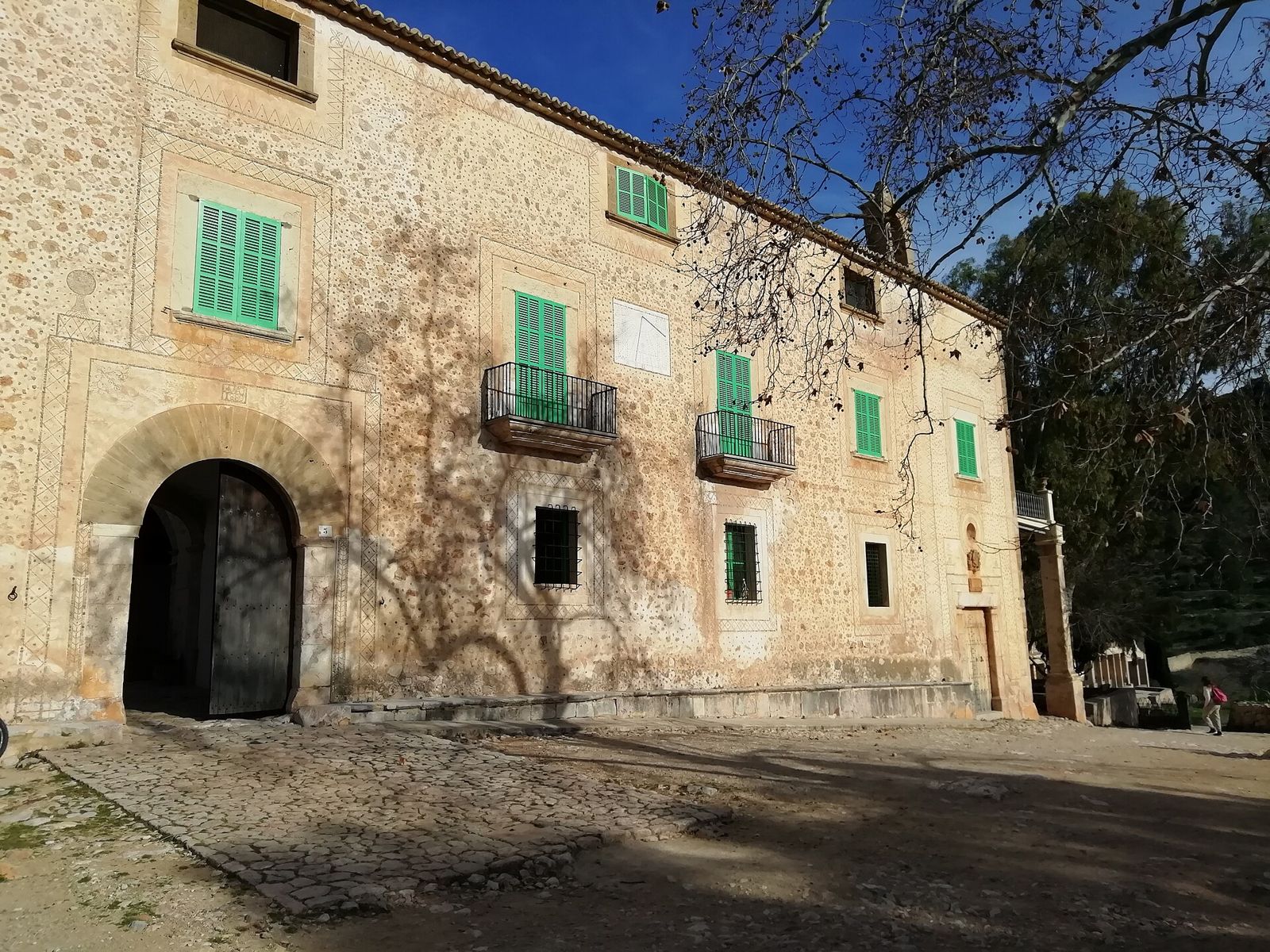 Steinfassade der Finca Galatzó mit grünen Fensterläden